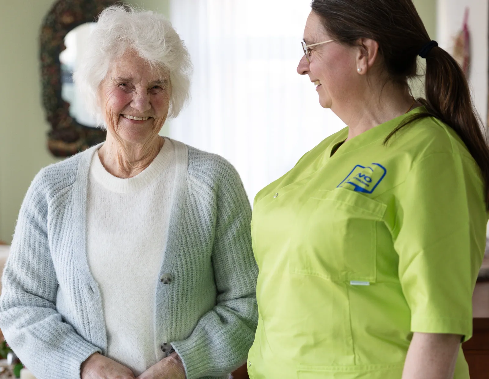 cliënt zorg aan huis en medewerker lachen wijkverpleging