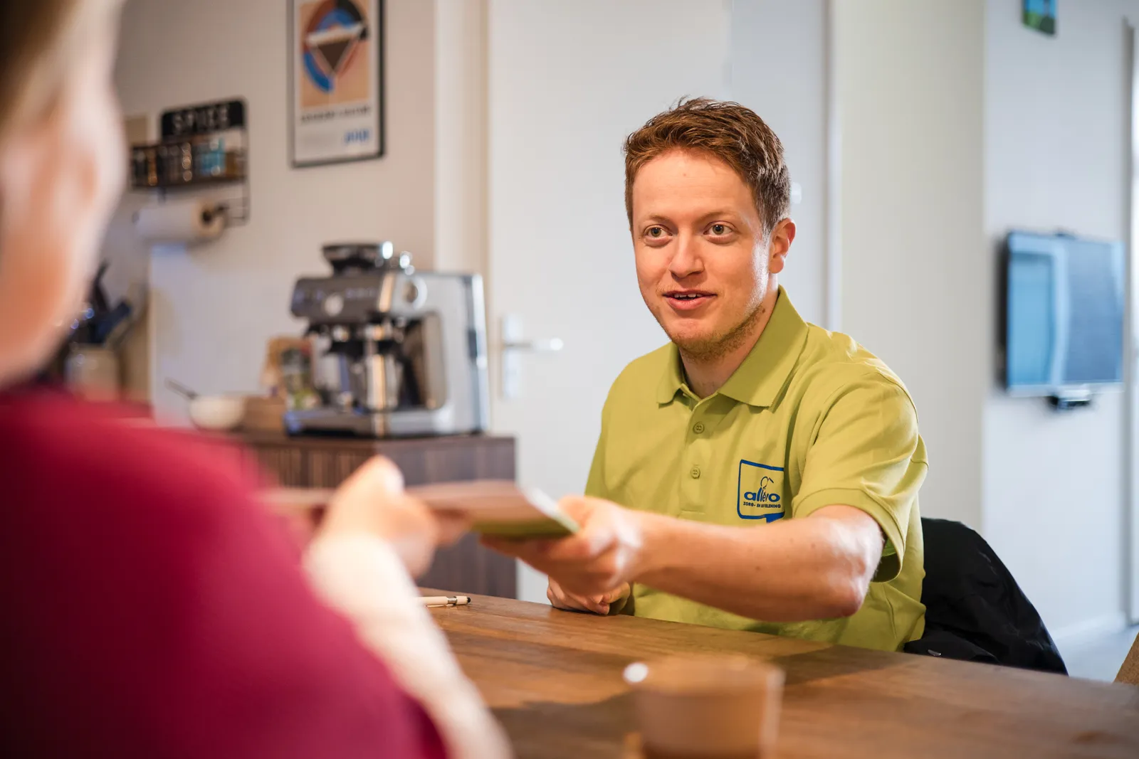 zittend aan tafel wordt de informatiemap overhandigd