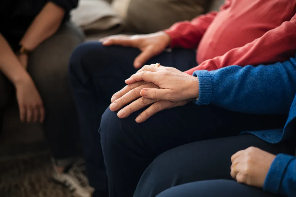 ondersteunende hand van vrouw bij man tijdens zorg aan huis