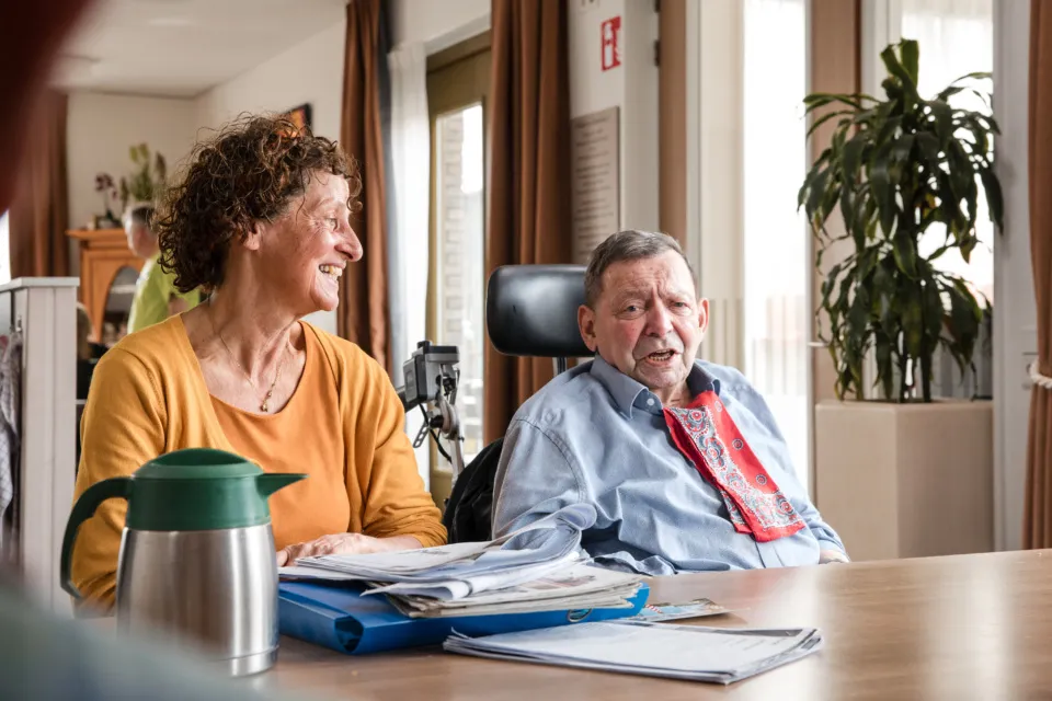 vrijwilliger en bewoner aan tafel en lachen vrijwilligers
