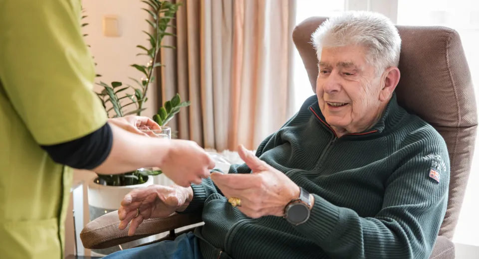 Medewerker rijkt medicatie aan aan cliënt.