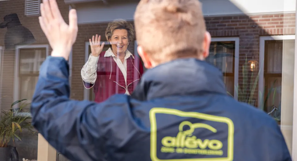 Medewerker zwaait naar cliënt in Allévo jas.