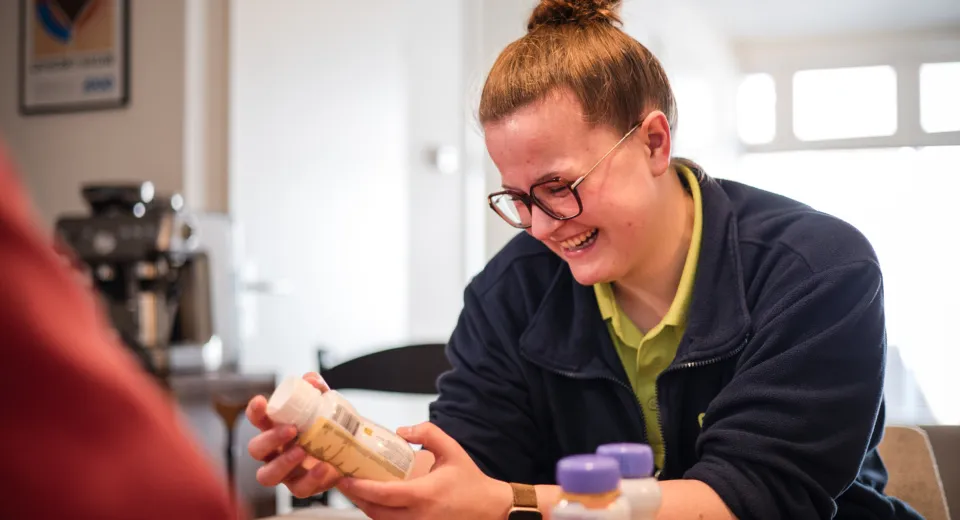 Medewerker kijkt naar nutridrink bij cliënt thuis.