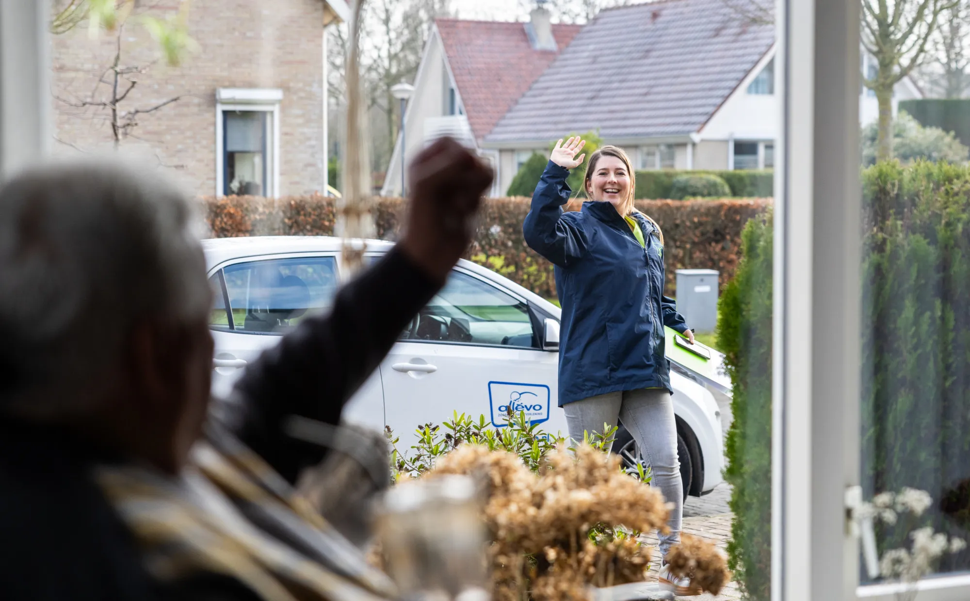 medewerker Allévo zwaait naar cliënt