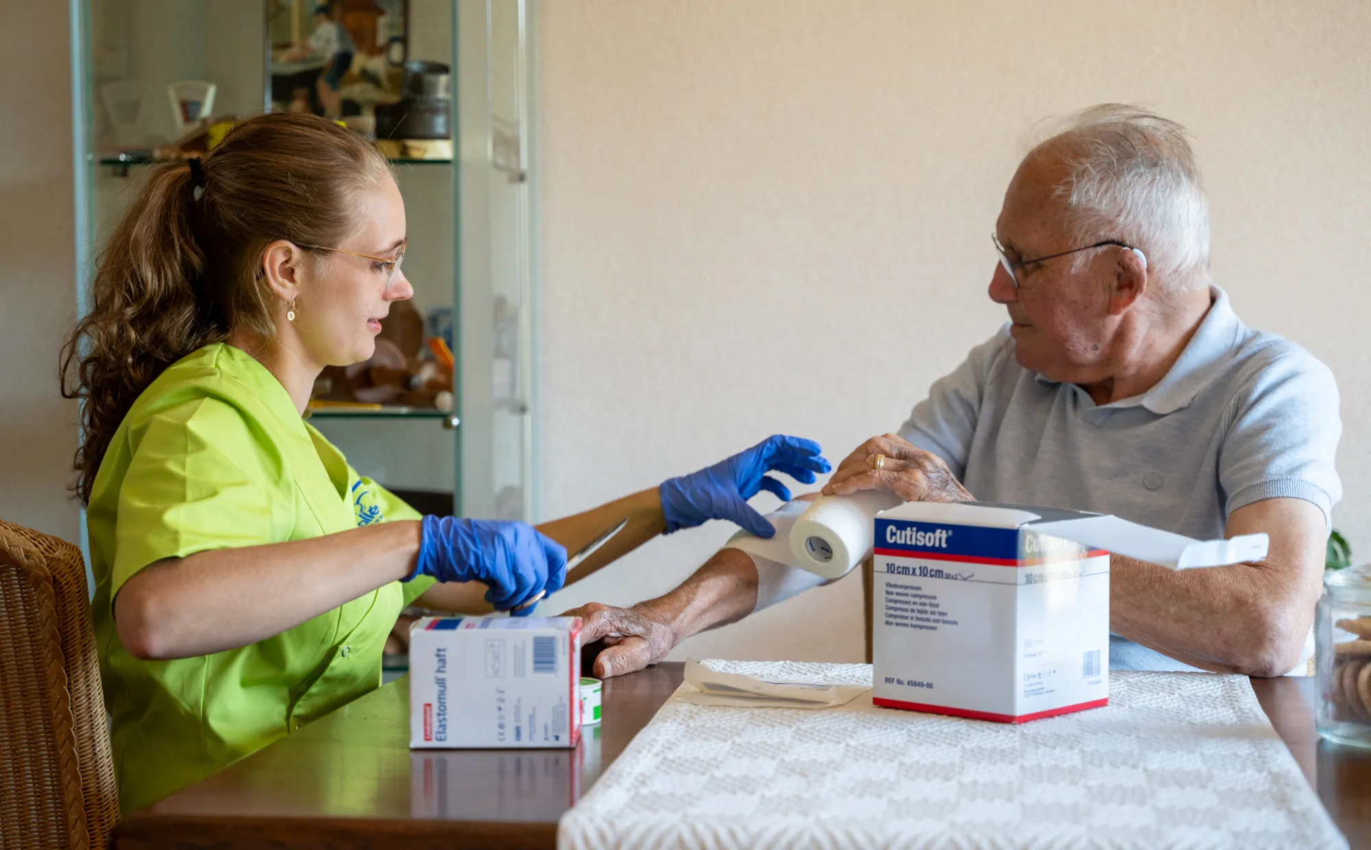 Medewerker legt verband aan op arm cliënt.