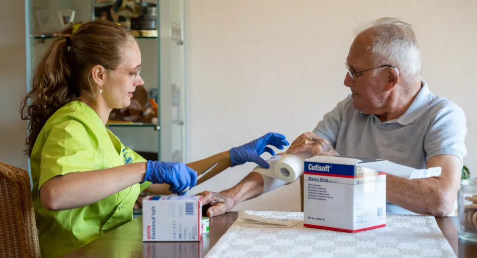 Medewerker legt verband aan op arm cliënt.