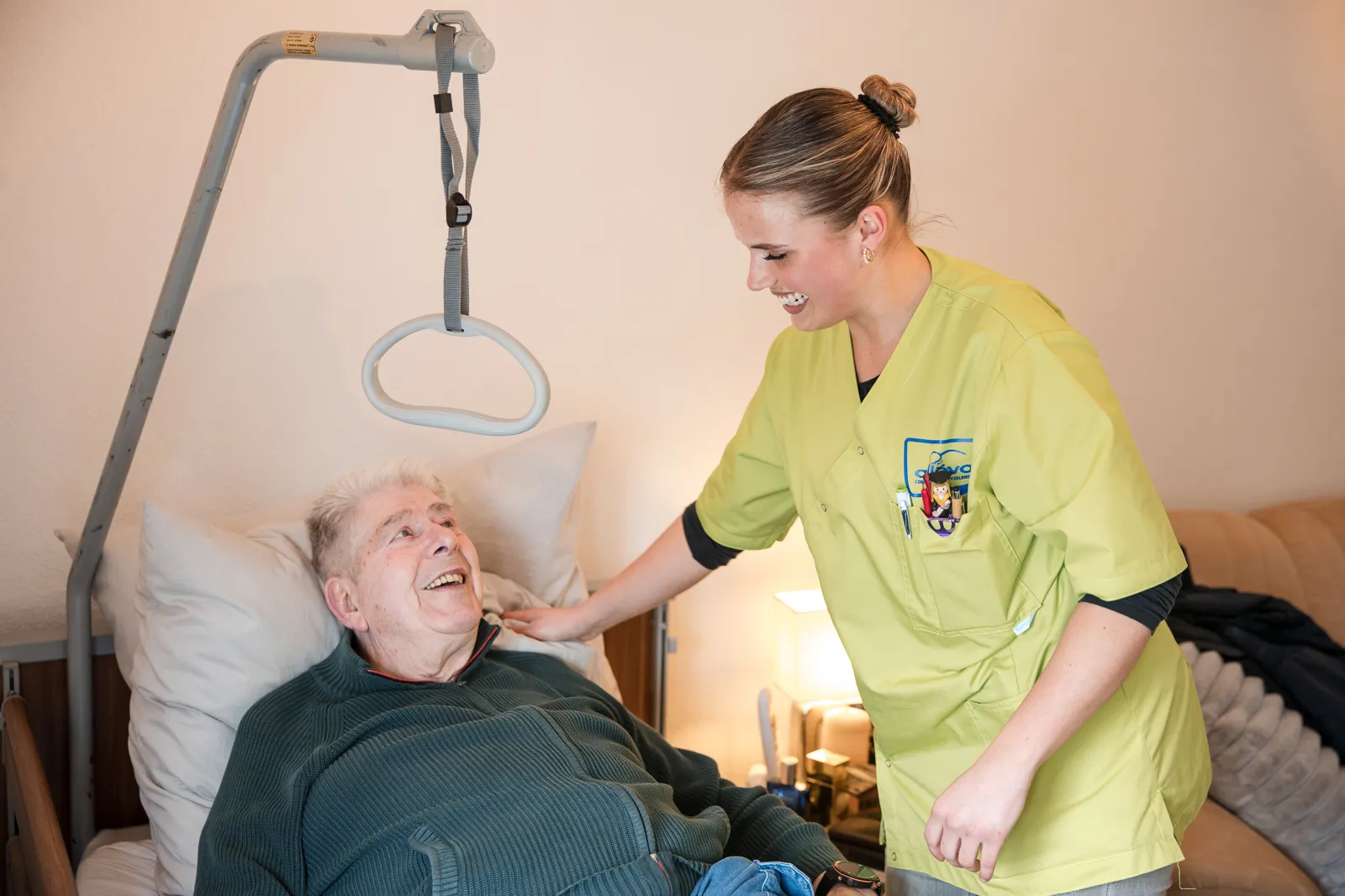 Verpleegkundige helpt cliënt in bed