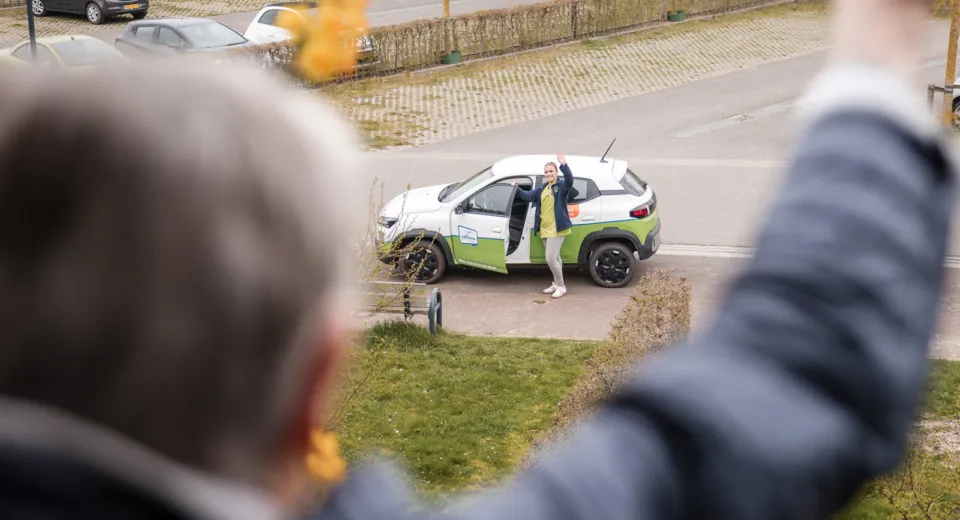 Verpleegkundige met auto in de wijk bij cliënt