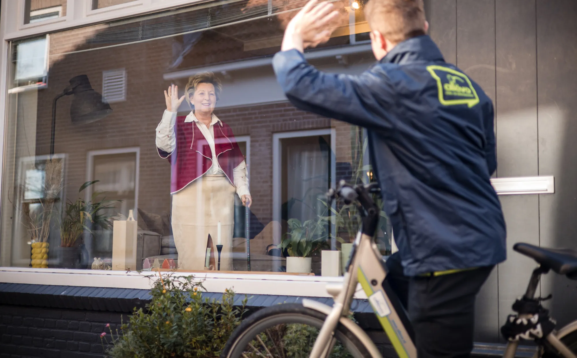 medewerker Allévo fiets zwaait naar cliënt