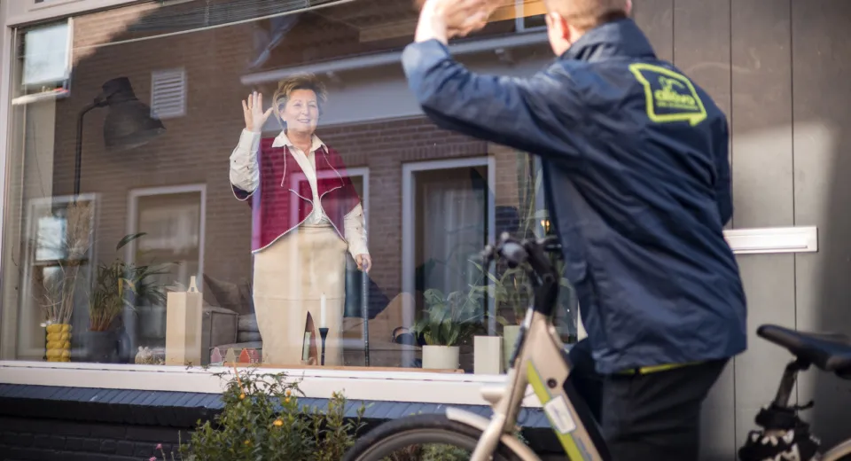 medewerker Allévo fiets zwaait naar cliënt